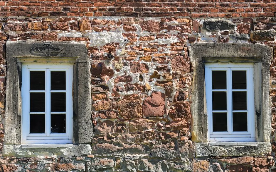 Façade d’une maison ancienne en pierre avec ses fenêtres à simple vitrage